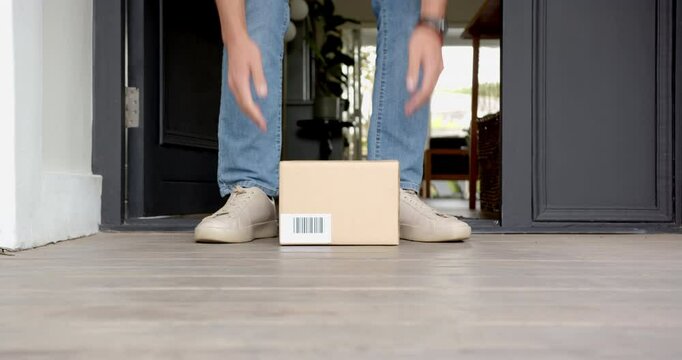 Receiving package delivery, man picking up box at home entrance, copy space