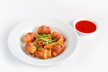 Fried sausages wrapped in bacon serve with mix vegetable, chili sauce and ketchup on white background