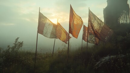 Worn prayer flags on a misty mountaintop at sunrise