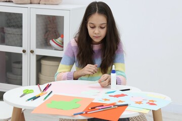 Girl making art project at table indoors