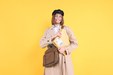Fototapeta premium Happy postwoman with bag and envelopes on yellow background