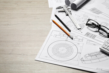 Different engineering drawings and tools on wooden table, space for text
