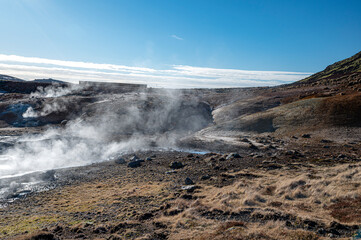 Seltun Geothermal Area - geyser on Iceland, steam rising from the geyser, on a blue sky day