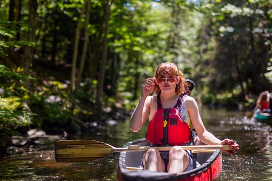 canoeing through a tranquil forested stream on a sunny afternoon