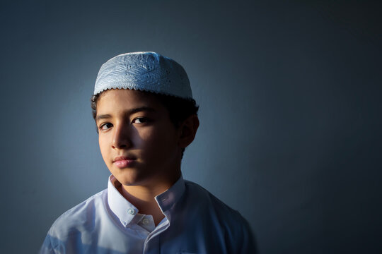 A close-up portrait of a young boy wearing traditional Islamic attire