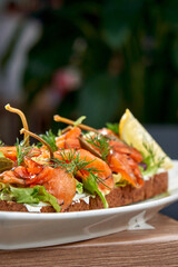 A vibrant and refreshing smorrebrod, a traditional Danish open-faced sandwich, topped with smoked salmon, fresh vegetables, herbs, and a creamy spread