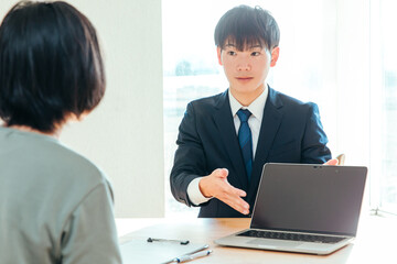 Fototapeta premium パソコンでお客様に案内する営業マン A salesman providing guidance to a customer on a computer