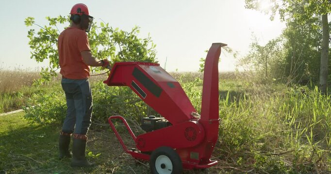 Garden worker using wood chipper shredder machine for making mulch