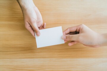 Obraz premium Warm Minimalism in Workplace Appreciation Close-up of Hands Passing Thank-You Card on Polished Wood - Boost Employee Morale in Modern Corporate Culture with Kind Gesture