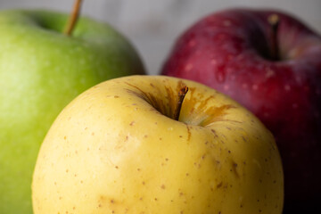Three apples of different varieties and colors: red, yellow, green
