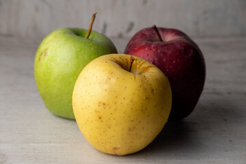 Three apples of different varieties and colors: red, yellow, green

