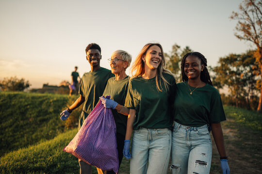 Volunteers carrying garbage bag enjoying teamwork cleaning park