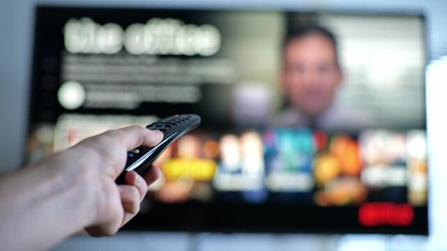 close up of hand browsing streaming service application on smart tv with remote control