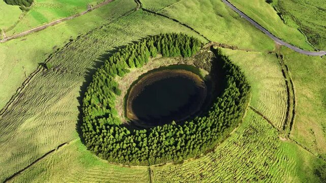 Pau Pique volcanic lake surrounded by trees, aerial tilt-up reveals coastline