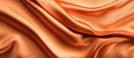 Fototapeta premium Orange silk fabric texture with smooth folds and gentle waves providing ample copy space for text placement.