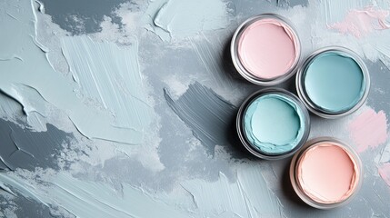 Four jars of pastel-colored paint arranged on a textured gray background with paint strokes and Copy Space for text insertion
