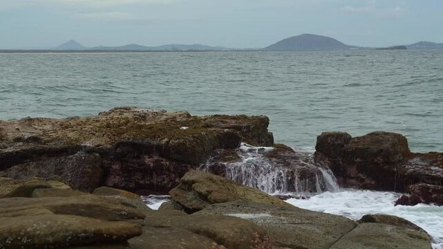Ocean waves crash against the rugged rocky shore at Point Cartwright, unleashing a powerful splash of seawater that soars high into the air, offering breathtaking views of the vast Pacific Ocean.
