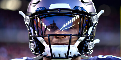 Close-Up of Football Player Wearing Reflective Helmet Visor. Close-up of an American football player wearing a blue helmet with a reflective visor. 
