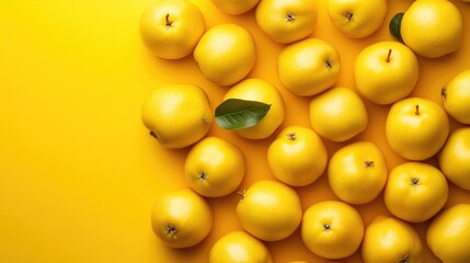 Fresh yellow pears arranged on a vibrant yellow background with green leaves offering ample copy space for creative text and design elements.