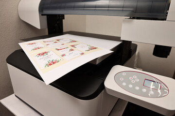 Modern printer with printed wedding invitation cards indoors, closeup. Printing house