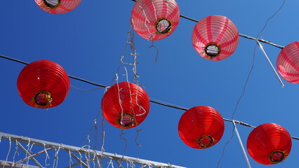 Red and pink lanterns under bright blue sky
