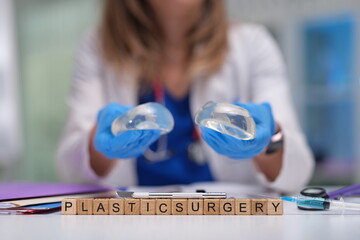 A plastic surgeon holds silicone implants in a clinical setting, emphasizing cosmetic surgery...