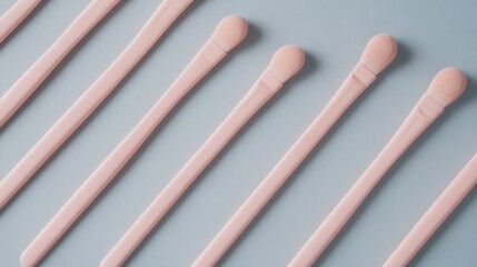 A flat-lay of minimalist makeup brushes with sleek handles, arranged diagonally on a pastel gray backdrop