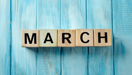 Wooden blocks with word March. New month. Spring time concept. Blue wood backdrop.