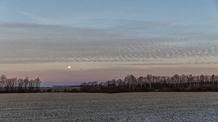A Beautiful Winter Morning Landscape Featuring a Stunning Full Moon Shining Brightly Over the...