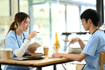 Medical students in scrubs studying anatomy with joint model on the desk