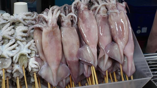 BANGKOK, THAILAND - AUGUST 2024 : View of grilled barbecue squid and octopus stick at the street food stall.