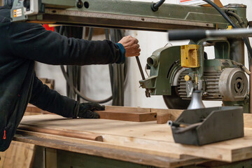 Un homme qui utilise une scie &agrave; bois. En pleine d&eacute;coupe d'un morceau de bois afin de r&eacute;aliser son projet.