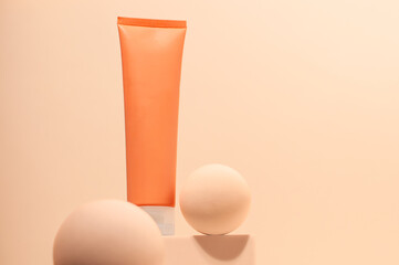 Orange cosmetic tube mockup on the podium with decorative balls. Beauty product display. Low angle view, below the eye line, looking up, hero view.