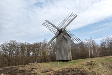 Historic wooden windmill in a serene countryside setting with autumn tones. A great choice for illustrating themes of tradition, rural life, and scenic landscapes
