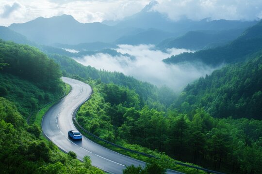 Scenic mountain road winding through lush green landscape with low clouds and serene atmosphere