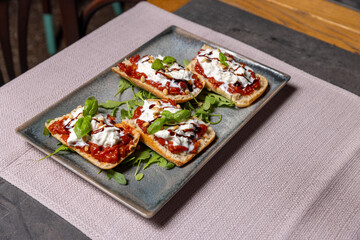Four bruschetta with peppers, cheese, and pine nuts served on a plate