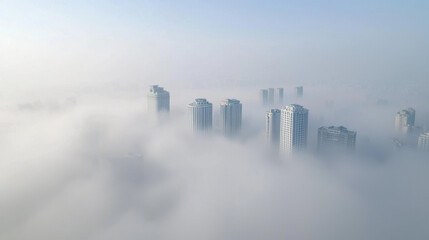 Fototapeta premium Aerial view of skyscrapers emerging from dense fog, creating mysterious atmosphere