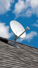 A white satellite dish is installed on a rooftop, clearly visible against a bright blue sky. This installation represents advancements in telecommunications history and technology