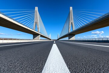 Impressive cable-stayed bridge spans across a smooth highway under a clear blue sky