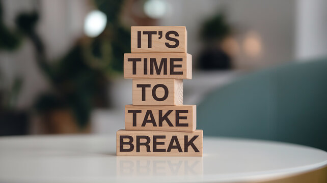 Stacked wooden blocks on a white surface read "IT'S TIME TO TAKE A BREAK" in dark brown sans-serif font. A blurred interior with plants and teal accents highlights the clean, calming design.







