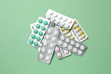 Pills in blister packs on green background, close up
