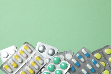 Pills in blister packs on green background, close up