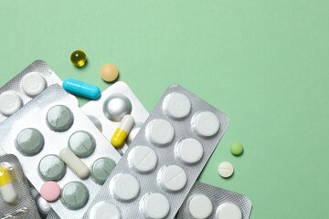 Pills in blister packs on green background, close up
