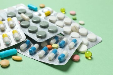 Pills in blister packs on green background, close up