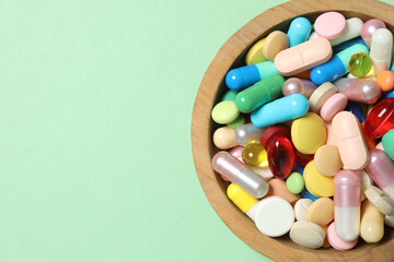Various pills in a bowl on color background