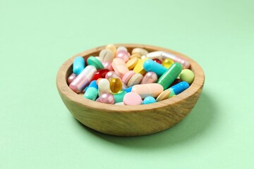 Various pills in a bowl on color background