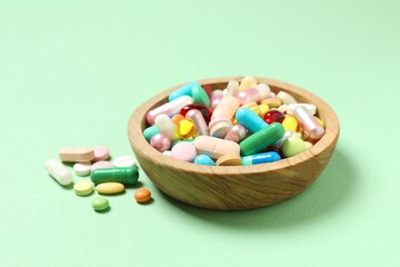 Various pills in a bowl on color background