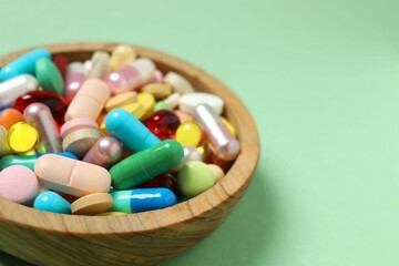 Various pills in a bowl on color background