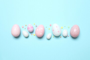 Colorful eggs, sweet sprinkles on pastel blue backdrop,  space for your text or advertisement