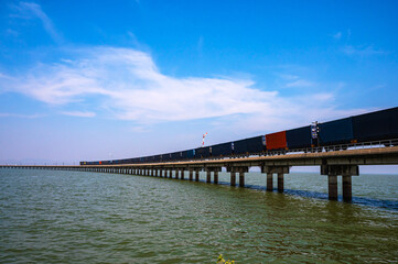 Fototapeta premium Floating commercial train on track crossing dam in Lopburi, Thailand